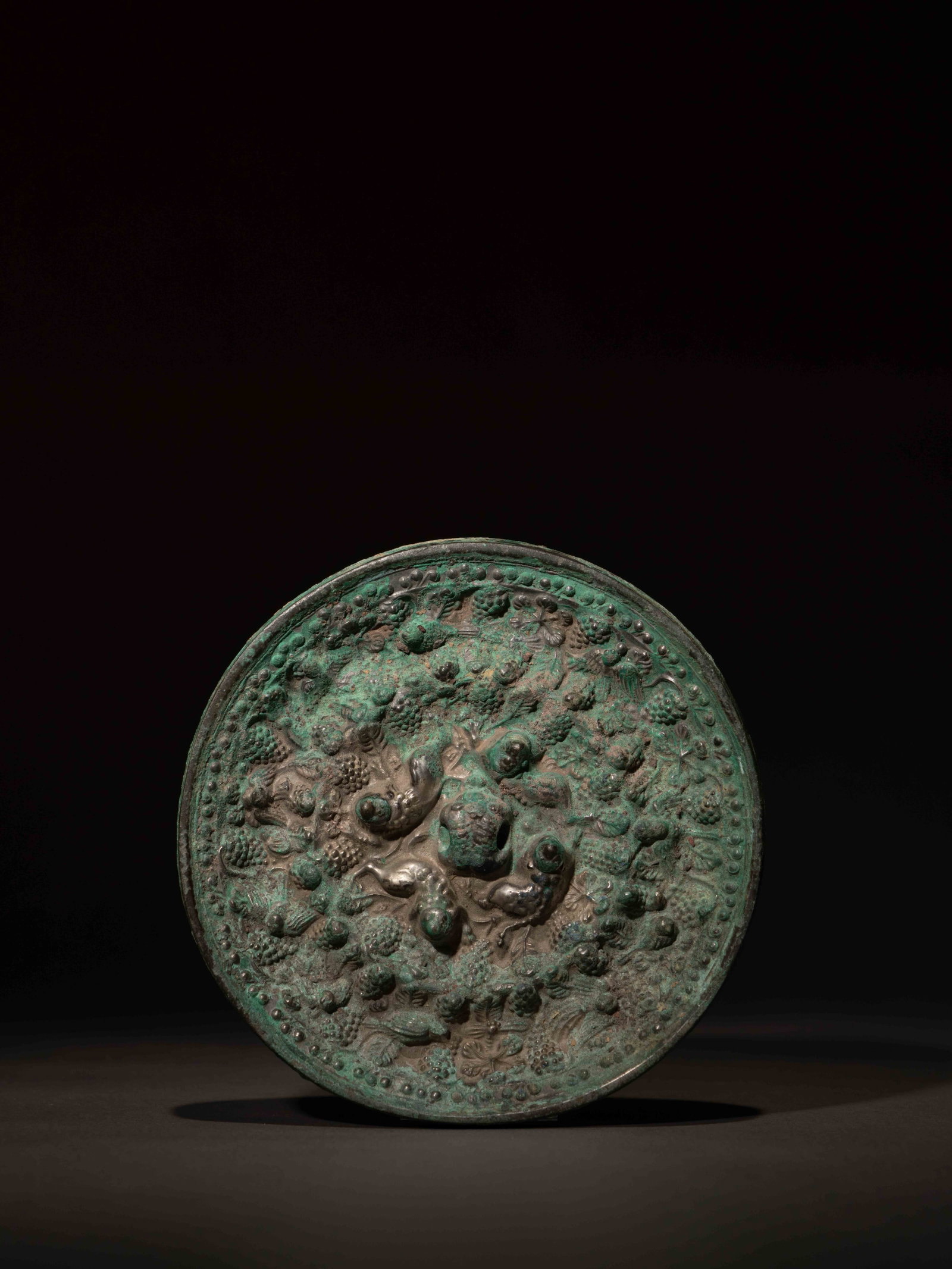 A BRONZE 'LION AND GRAPEVINE' MIRROR: 年代(Age):TANG(618-907 A.D.) 。尺寸(Size):11.3 cm Diameter。 來源：日本私人收藏。