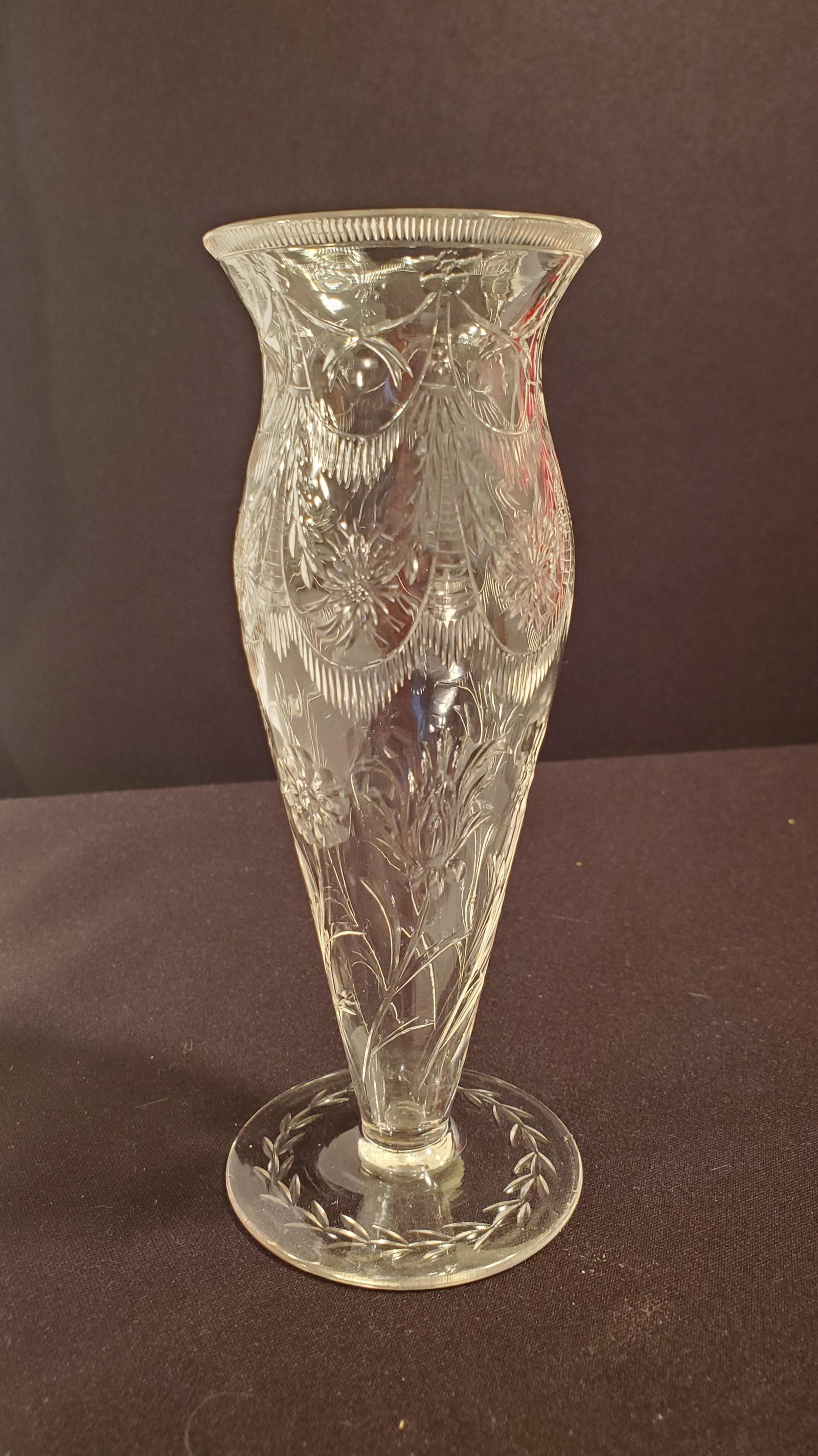 Clear Cut Glass Bud Vase: Clear Cut Glass Bud Vase with beautiful depiction of flowers and swags of garland along the top. 6 inches Tall, 2 1/4 inches at the base and 2 inches at the mouth.