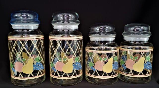 Collection of Four Vintage Kitchen Canisters: Four canister collection with decorative fruit design with lids. Two are 6.5" tall and 4" wide. Two are 8.5" tall and 4" wide.