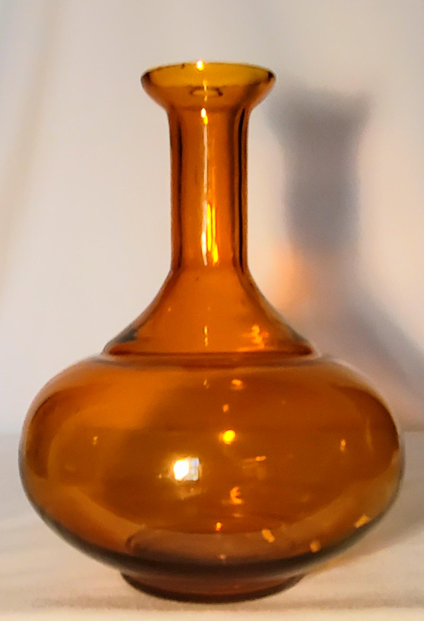 Bottle Shaped Amber Glass Vase: 9" tall with 2.5" opening and 4" base; This vase give you the freedom to mix and match, or just match, your single flower stems. This bottle shaped, amber glass bud vase pair well with other amber vas