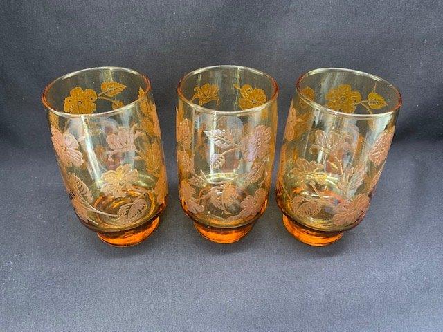 Three Embossed Amber Glass Tumblers: Mid century modern footed amber glass tumblers with embossed floral design.