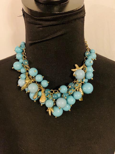 Modern Charm Style Confetti Necklace in Lake Blue: Lovely matte blue beads in grouping of "confetti" style complemented by sea shore theme charm. All Items generally inspected during cleaning for damage etc. All items are in good wearable/sellable con