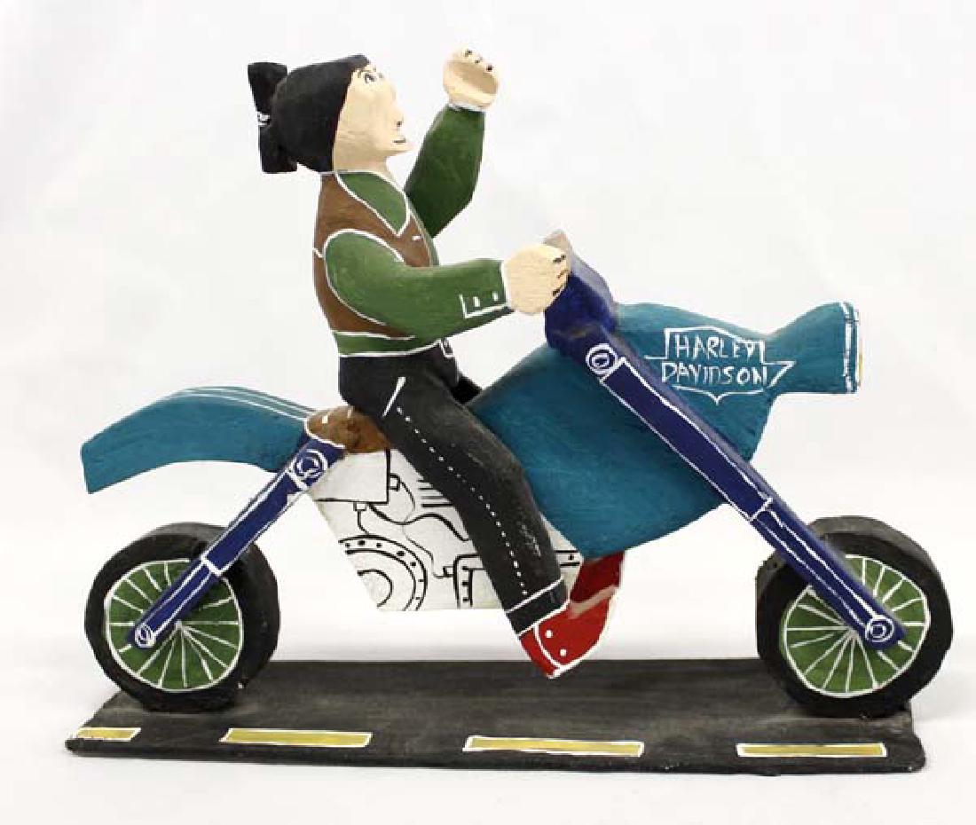 Navajo Carved Wood Folk Art Harley Davidson, Buck: Native American Navajo Carved Wood Whimsical Folk Art Harley Davidson by Delbert Buck, signed by artist and measures 10 3/8''L x 7.75''H x 2''W, features Navajo man riding Harley wearing red cowboy bo