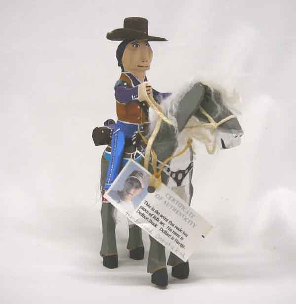 Navajo Folk Art By Delbert Buck 8'': Navajo Folk Art By Delbert Buck 8''. Cowboy on ''donkey''. Certificate of Authenticity attached to folk art. SHI $20.