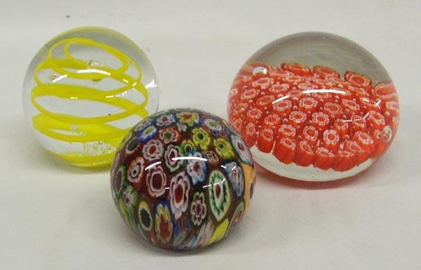 Three Glass Paperweights Murano Milleflorie: Three Glass Paperweights includes Murano with old label-Italy, Milleflorie, and Yellow ribbon capturing a blown bubble, largest measures approx. 2.5'' x 3.25''. SHI $25.