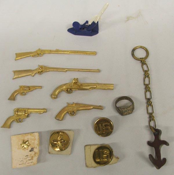 Military Collectibles: Collection of Military Collectibles which includes: pins, ring, anchor key chain, cast iron toy guns, plastic USA rocket launcher, ring size 11.5, largest cast iron gun measures 4.75'' long. SHI $15.