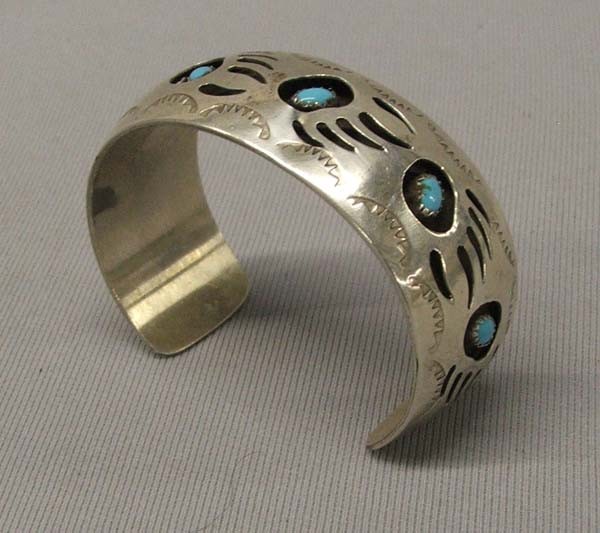 Hopi Silver Turquoise Bracelet by Pearlene Spencer: Hopi Silver Turquoise Shadow Box Bracelet by Pearlene Spencer. Bracelet has 6 Bear Paws with Turquoise Stone. One Paw Print has damage to it. Measures 7.25''x.875''. SHI $15