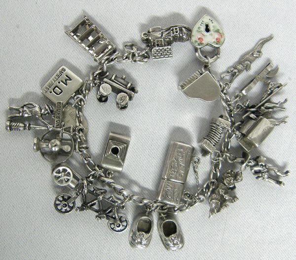 Sterling Silver Charm Bracelet: Sterling Silver Charm Bracelet with 21 miscellaneous Charms, 9 are marked sterling and we believe that most of the others are silver as well, charms include heart locket, grand piano which opens up, c