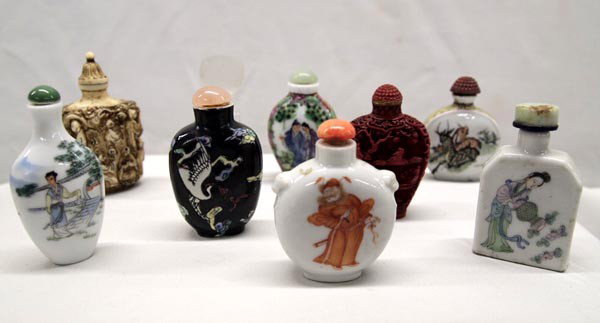 Chinese Snuff Bottles: 9 Chinese Snuff Bottles. Some made of porcelain, cinnabar, bone and jade. One bottle is a clear French glass perfume bottle (Lancome) with carved top. Largest measures 3 1/4'' x 2''. Buyers Pay Actual
