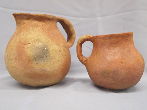 2 Pair Taos Micaceous Pottery Pitchers: 2 Pair Native American Taos Micaceous Pottery Pitchers. Both have sage smudge sticks and herbs inside, for ceremony. The larger one measures 6''x6'' and the smaller is 4.75''x5''. Buyers Pay Actual Sh