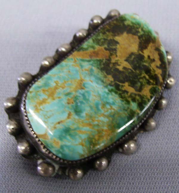 1950 Navajo Sterling Silver & Turquoise Pin: 1950 Navajo Sterling Silver & Turquoise Pin. Irregular polished turquoise stone set in a bead-work setting. Measures 2'' x 1'', original clasp has been replaced. Buyers Pay Actual Shipping and Handlin