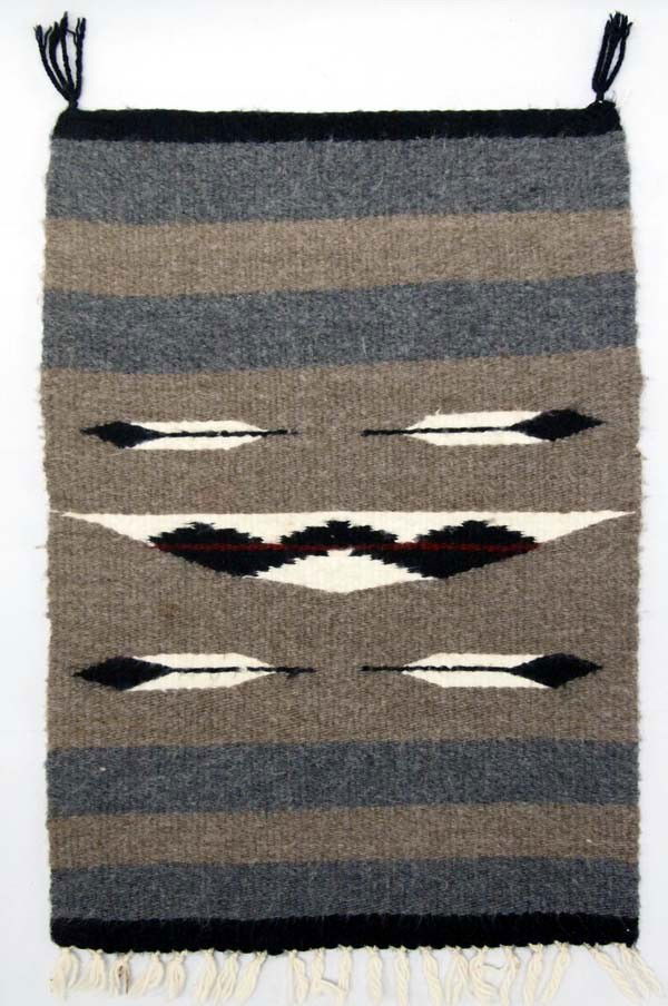 Navajo Pictoral Sampler Rug: PUEBLO: Navajo ETHNICITY: Native American DESCRIPTION: There is a basket design on this rug. Above and below the basket are feathers. Sampler size rug from Shiprock, NM. SIZE: Measures 20''x13.5''. Bu