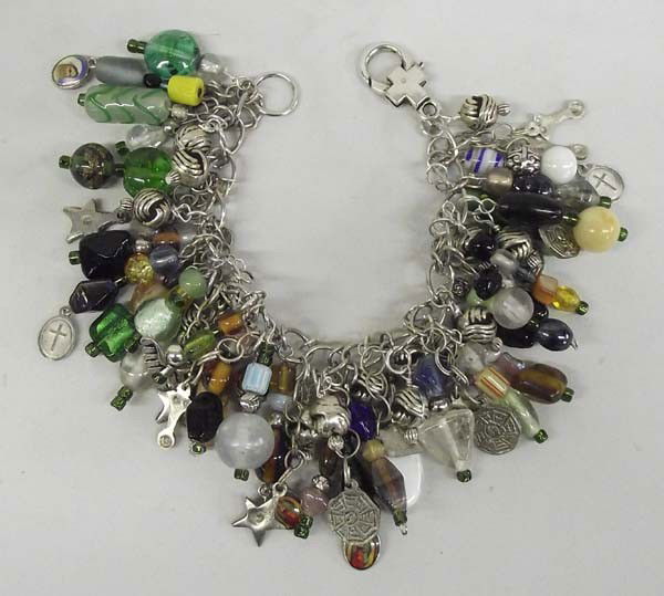 Quail Ridge Sterling Glass Bead Charm Bracelet: DESCRIPTION: Chain bracelet full of glass bead, lamp work bead, some sterling charms, many religious charms. Quail Ridge is a local Silver City, NM artist. SIZE: Bracelet measures 8.25''. A pendant ch