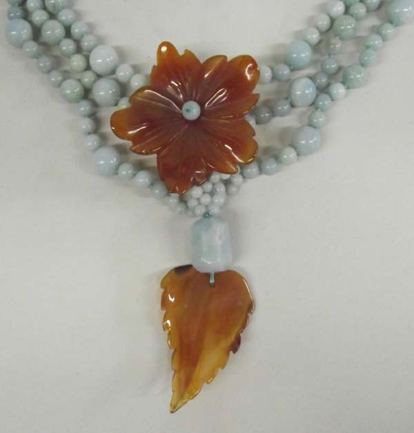 Natural Amazonite Carnelian Necklace: DESCRIPTION: Three strands of blue green amazonite beads with carved carnelian flower and leaf accent beads. SIZE: Necklace measures 20'' end to end. The pendants are approximately 2'' long.