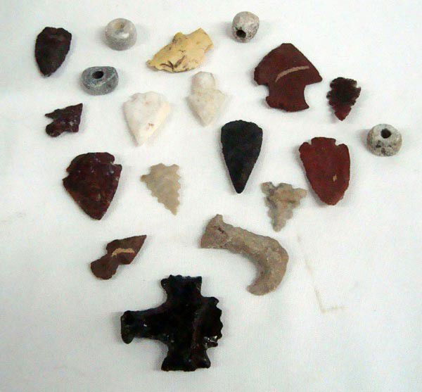 Stone Arrowheads and Stone Beads: AGE: Age and origin unknown DESCRIPTION: Approximately eighteen stone collectibles including arrowheads, fish hook, game pieces and beads. Some obsidian. SIZE: Largest approx 1.75''L x2''H.