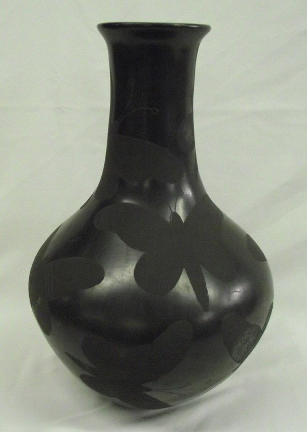 Mata Ortiz Black on Black Butterfly Jar - T Tena: PUEBLO: Mata Ortiz ETHNICITY: Mexican DESCRIPTION: Tall burnished black jar with large butterfly images. Signed on the bottom. SIZE: 13''Hx9''W (diameter at widest part).