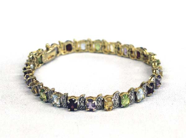 Gold Overlay on Sterling Silver Gemstone Bracelet: Gold Overlay on Sterling Silver Gemstone Bracelet, measures approx.7.25'' end to end x .25'' W. Tennis Bracelet features Citrine, Amethyst, Ruby & Peridot Stones.