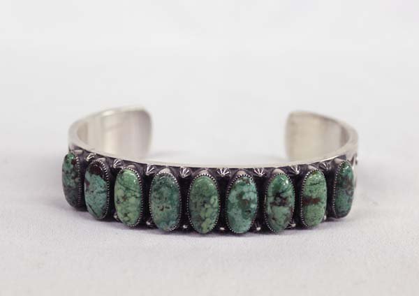 Navajo Sterling Turquoise Bracelet by Kirk Smith: Native Navajo Sterling Silver Turquoise Bracelet by Kirk Smith. Inside measurement is 7.5'' x width of 5/8''. There are nine beautiful turquoise stones around this bracelet. The inside has wonderful s