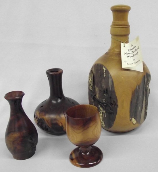 3 Wood Turned Bottles, 1 Turned Goblet: 3 Wood Turned Bottles, 1 Turned Goblet. The stoppered bottle stands 10'' tall x 5'' wide is is turned from a fence post, inscribed ''Totara Fence Post Bottle 1917 NZ'' by artist Ken Godwin. The 2 bott