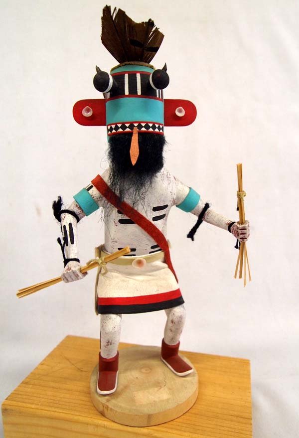 Navajo Corn Whipper Kachina: Native American Navajo Corn Whipper Kachina. Brightly colored kachina, measuring 9'' tall with a base of 3''. Feather headdress with applied shells around his belt and ears.