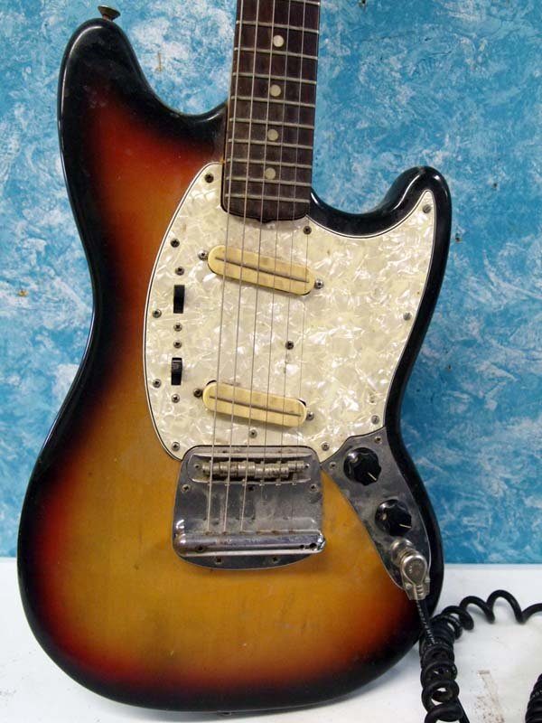 Fender ''Mustang'' Electric Guitar With Case, Stand: Fender ''Mustang'' Electric Guitar With Case, Stand. Has amplifier cord and works. Also has a shoulder strap. Guitar is 39.5''Lx11.75''W. Plays well. Finish is worn on back and along top edge. The cas
