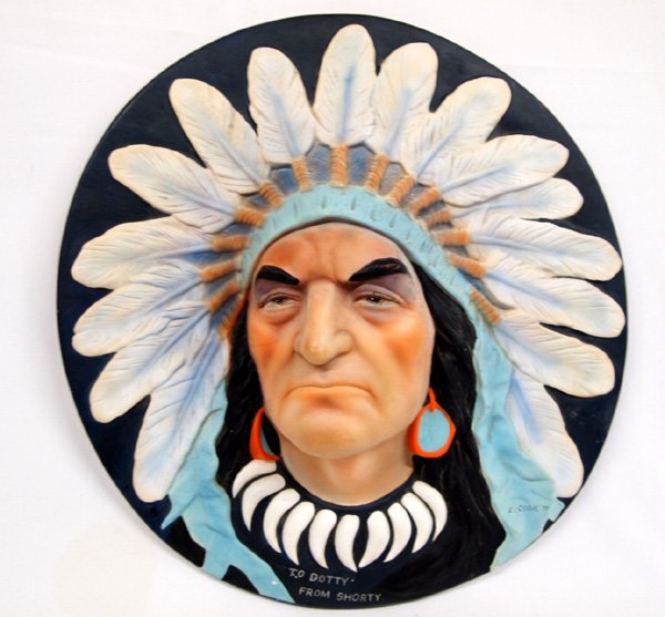 Ceramic Chalk Indian Chief Face Wall Hanging: Ceramic Chalk Indian Chief Face Wall Hanging. by E. Cook 1979, and printed on the bottom, TO DOTTY FROM SHORTY which could be painted over. Hole on back for hanging. Approx 17'' diameter.