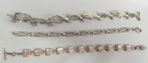 3 Sterling Silver Link Bracelets: Three Bracelets of Multiple Sterling Styles. 10 Sterling fish stamped 925 and sterling is 7''L. 2) Each pink shell back is stamped SANEL. 6.75''L with toggle clasp 3) Heart and box chain bracelet 925