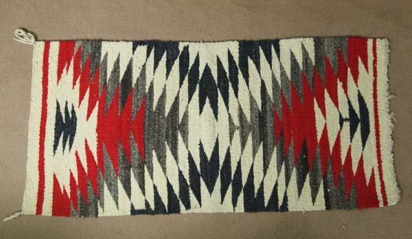 Navajo Weaving: Navajo Weaving. Grey, black, red and off white. 38''L x 17''W. Navajo weaving are not only beautiful, well-woven textiles but they so accurately mirror the social and economic history of Navajo people