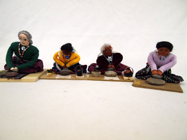 Four Navajo Women Dolls, Grinding Corn: Four Navajo Women Dolls, Grinding Corn. 3''H x 5.5''L. Cute models of Navajo women grinding corn with manos on matates. Two have cradleboard babies.