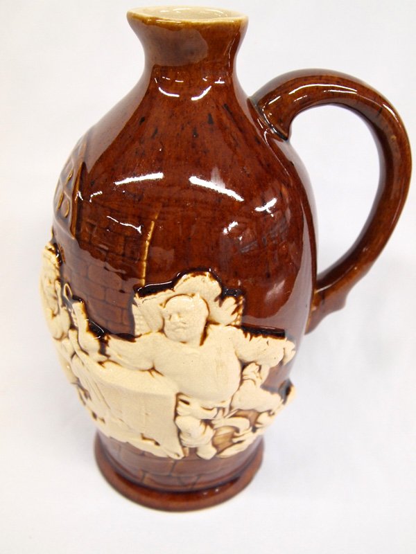 German Antique Raised Relief Pitcher: German Antique Raised Relief Pitcher. 9.5''H x 8''W a tavern scene with men drinking from steins raised in off white color on a brown background. Bottom is marked Made in Germany with the number 2043.