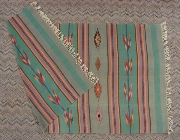 Large Mexican Textile: Large Mexican Textile. Measures 82''L x 46''W. With storm designs of pastel teal, pinks, and more, this soft textile can serve many uses. Off white fringe.