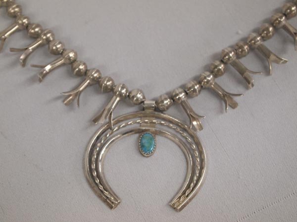 Sterling Silver Navajo Squash Blossom Necklace: Sterling Silver Navajo Squash Blossom Necklace. Single strand of hollow silver balls hold squash blossoms and a simple Naja with rope twist braid center and a turquoise cabochon. Necklace is 24'' end 