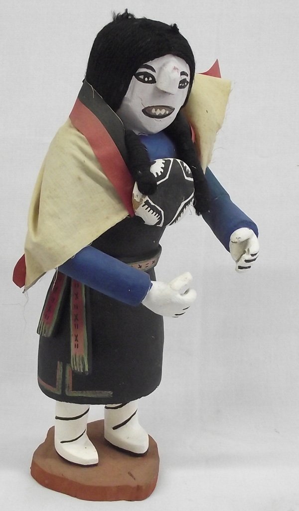 Hopi Carved Wood Kachina: Hopi Carved Wood Kachina. Older, tall kachina with cloth blanket on and large ''medalion'' holding it closed. Measures 15''H x 8''D x 8''W. Signed on the bottom, ''Tom 82''.