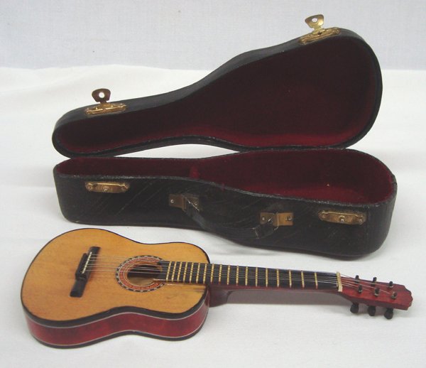 Miniature Guitar and Hard Case: Miniature Guitar and Hard Case. Incredible detail on this miniature guitar and case. The guitar measures 7-3/4''L x 2-7/8''W x 3/4''D. The string pegs do turn. The case is lined with red velvet and ha