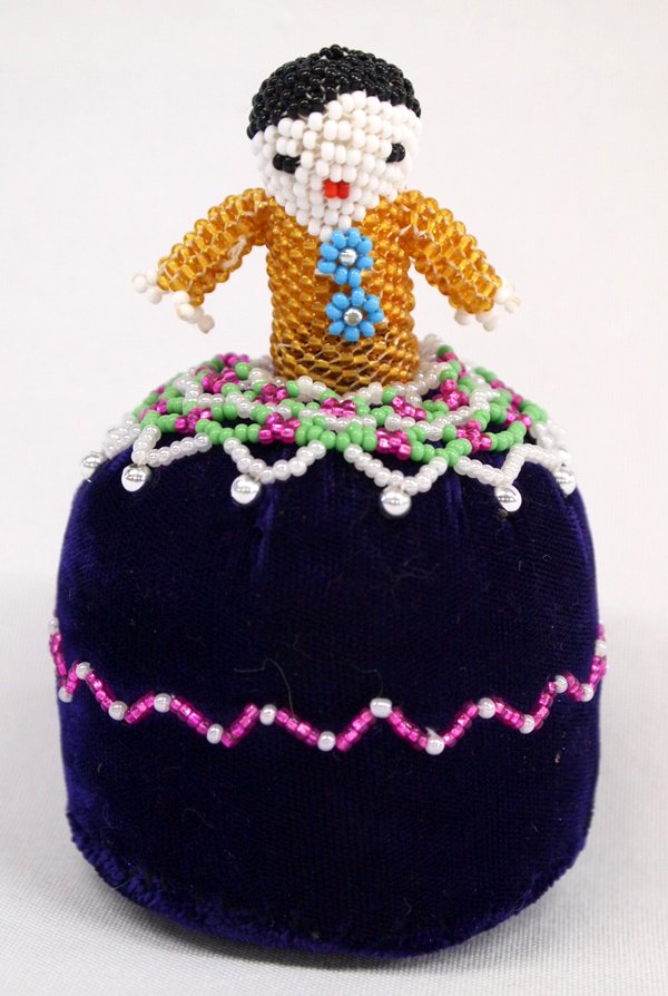 Navajo Beaded Pincushion Doll: Navajo Beaded Pincushion Doll. Nicely beaded doll, gold beads with turquoise necklace, fancy beadwork around the skirt of dark purple velvet. Measures 4'' tall and 2'' wide.