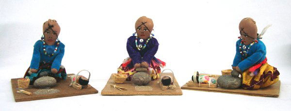 3 Navajo Cloth Doll Figures Grinding Corn: 3 Navajo Cloth Doll Figures Grinding Corn. These are three similar scenes of a Navajo woman grinding corn on a stone metate with a stone mano. An infant in a cradle board lies next to her. Each doll i