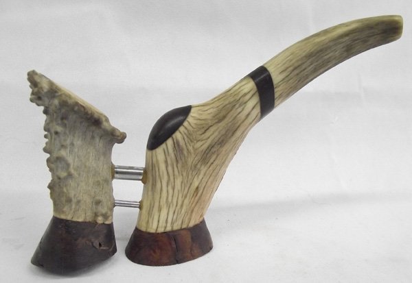 Antler Horn Custom Made Pipe: Antler Horn Custom Made Pipe. Two sections of horn are joined by two hollow metal pipes and there is inlaid wood trim and bases. It measures 5''H x 7.5''L.