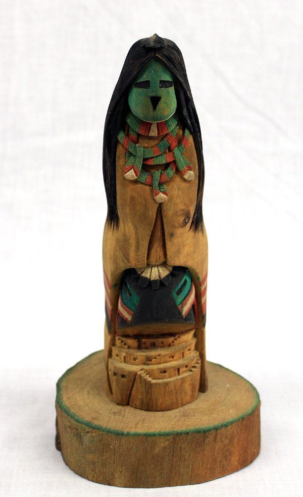 Hopi Hono Blue Mana Long Hair Kachina by T Francis: Hopi Hono Blue Mana Long Hair Kachina by Ted Francis, Jr., measures 9''H, features Kachina standing atop pueblo, on wooden base, name of kachina and artist's name woodburned on the bottom