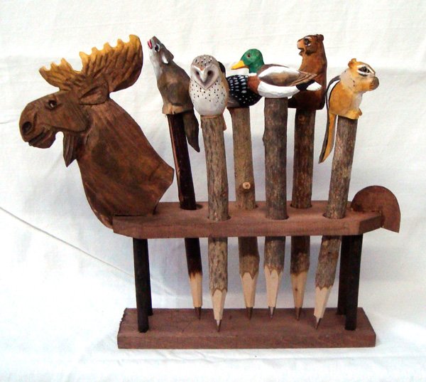 Set of 6 Carved Animal Pens in Carved Moose Stand: Set of 6 Carved Animal Pens in Carved Moose Stand. This cute item has 6 pens that are painted and depict a Chipmunk, Loon, Squirrel, Mallard, Wolf, and Owl. They sit in their own moose holder. The pen
