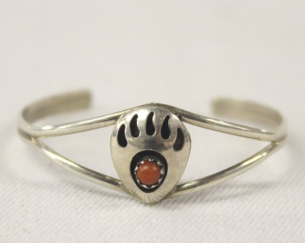 Navajo Sterling & Coral Bear Paw Child's Bracelet: Navajo Sterling & Coral Bear Paw Child's Bracelet. Sweet little child's bracelet with a small coral stone set in the traditional symbol of a bear's foot. Measures, including opening, 4'' x .5'' wide.