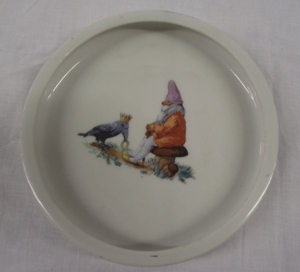 Antique German Ceramic Baby Bowl: Antique German Ceramic Baby Bowl, measures 1''H x 6.75''D, features seated gnome on toadstool with a crow wearing a crown and carrying a gold ring, bottom of bowl is stamped 1363/1 and Germany 12