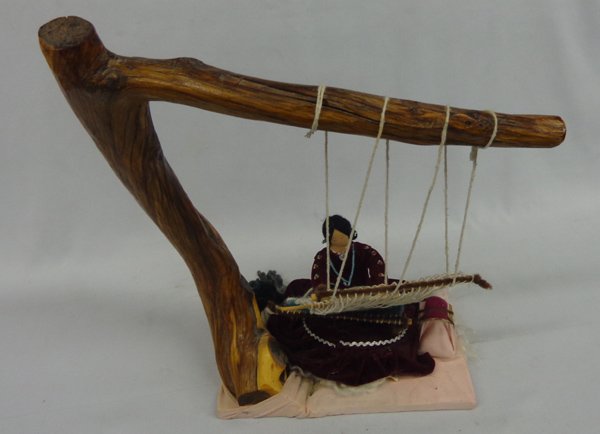 1998 Navajo Weaver Doll by artist Alice M. Brown: Navajo Weaver Doll with Cypress Wood. Large Navajo weaver doll sitting at her loom with her baby in her cradle board, maroon velvet authentic costume. Measures 16 1/2'' high, overall width approximate