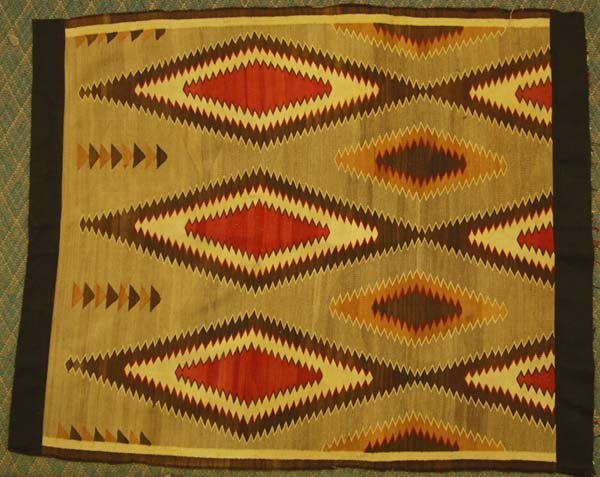 1940's Navajo Traditional Rug: 1940's Navajo Traditional Rug. This textile has been cut in half and the raw edge lined in material. It measures approx. 50.5''W x 62''L and has a wonderful design in browns and reds.