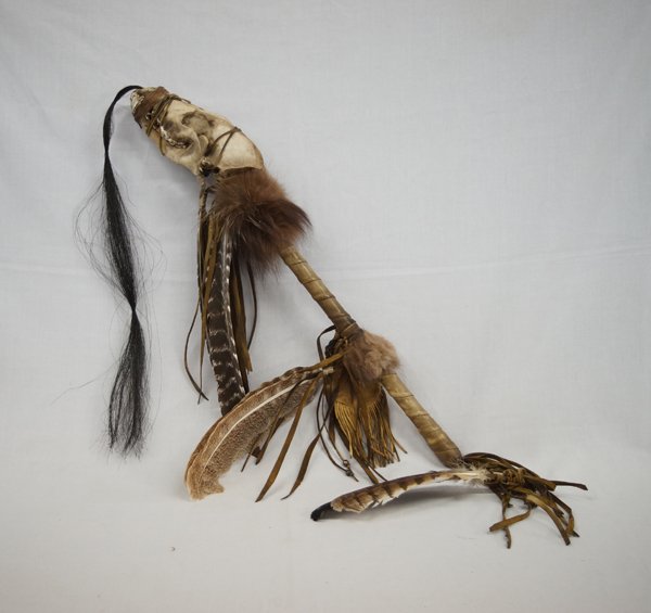 Plains Indian Coyote Skull Rattle: Plains Indian Coyote Skull Rattle, measures 24''L x 4''W, embellished with horse hair, feathers, fur, leather fringe, and hide wrapped shaft