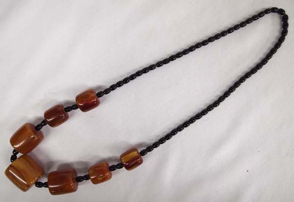 Genuine Amber & Obsidian Bead Necklace: Genuine Amber & Obsidian Bead Necklace. This piece has 7 Large Cylindrical amber beads interspersed with small oval shaped obsidian beads. It measures approx. 26'' end to end with the larges amber bea