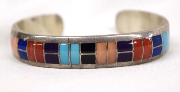 Zuni Sterling Channel Inlay Bracelet, Ted Tsadiase: Native American Zuni Sterling Channel Inlay Bracelet by Ted Tsadiase, inside measures 6.75'' which includes opening x .5''W, inlay includes angel coral, red coral, jet, turquoise, and lapis, hallmarke