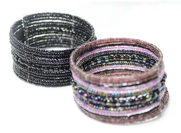 2 Round Beadwork on Springwire Bracelets: 2 Round Beadwork on Springwire Bracelets, one is black and the other is purple and black