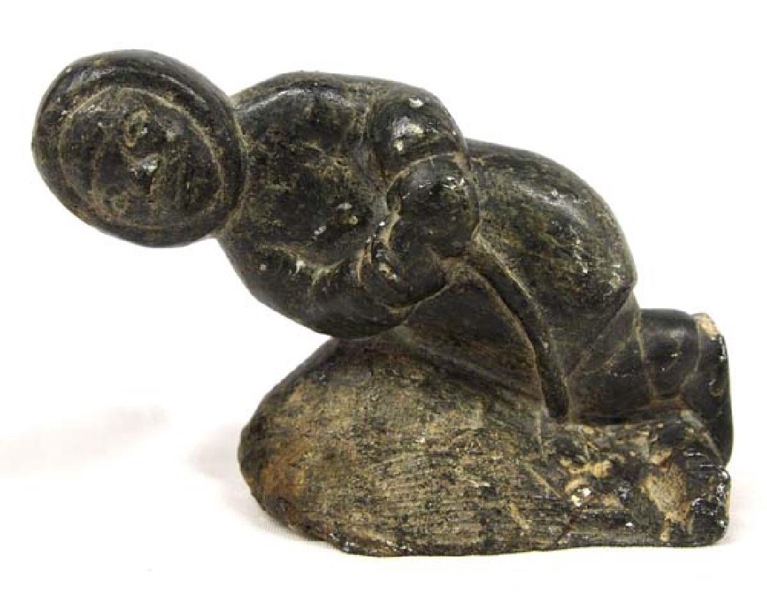 Canadian Inuit Carved Stone Fisherman by Aculiak: Native American Canadian Inuit Carved Stone Fisherman by Daniel Aculiak (1944-present), measures 4'' x 5.25'' x 2.25'', signed in Inuktitut and with disc number, this piece has a chip out of the fishe