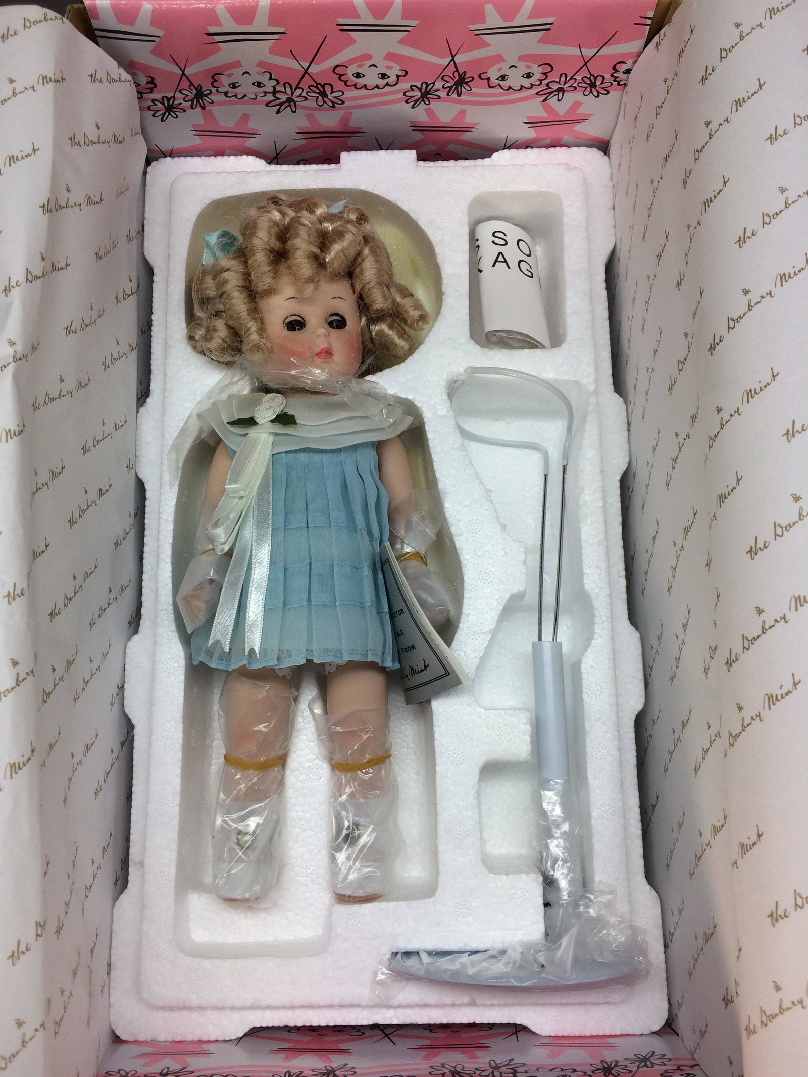 Shirley Temple Ginny Porcelain Doll NRFB Danbury: Ginny channels Shirley Temple in this 10.5” all porcelain doll with blonde curls and hazel sleep eyes. Her pleated organdy dress evokes Shirley’s wonderful movie costumes of the 1930s. Made by the