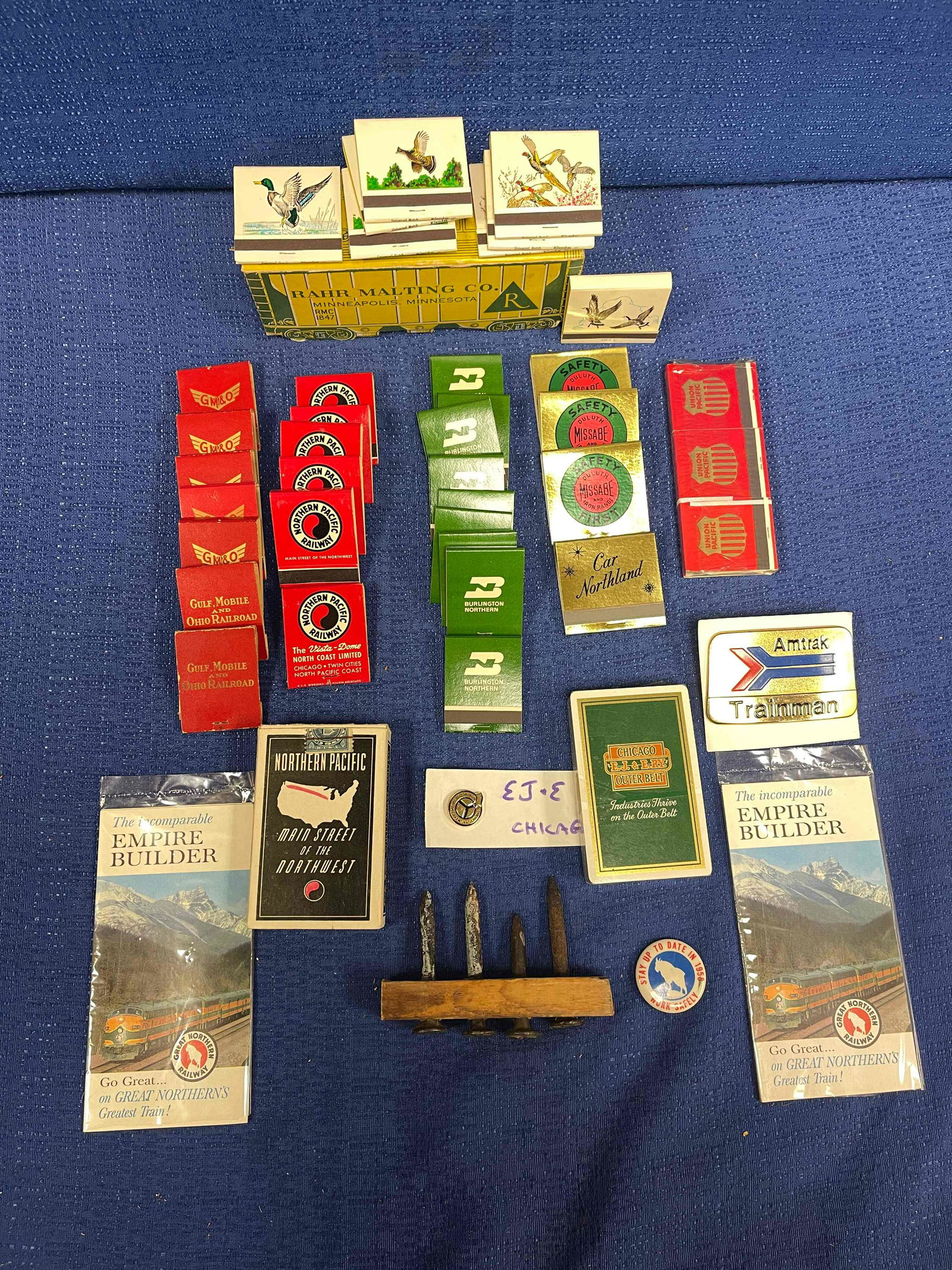 Railroad Collectibles Lot: 5 Railroad Nails Marked; 1 Amtrack Trainman Badge; 1 Elgin, Joliet, and Eastern Railroad Cards: 1 Northern Pacific Cards; 2 Great Northern Fold-outs; 1 Elgin, Joliet, and Eastern Pin; 9 Books of Burli